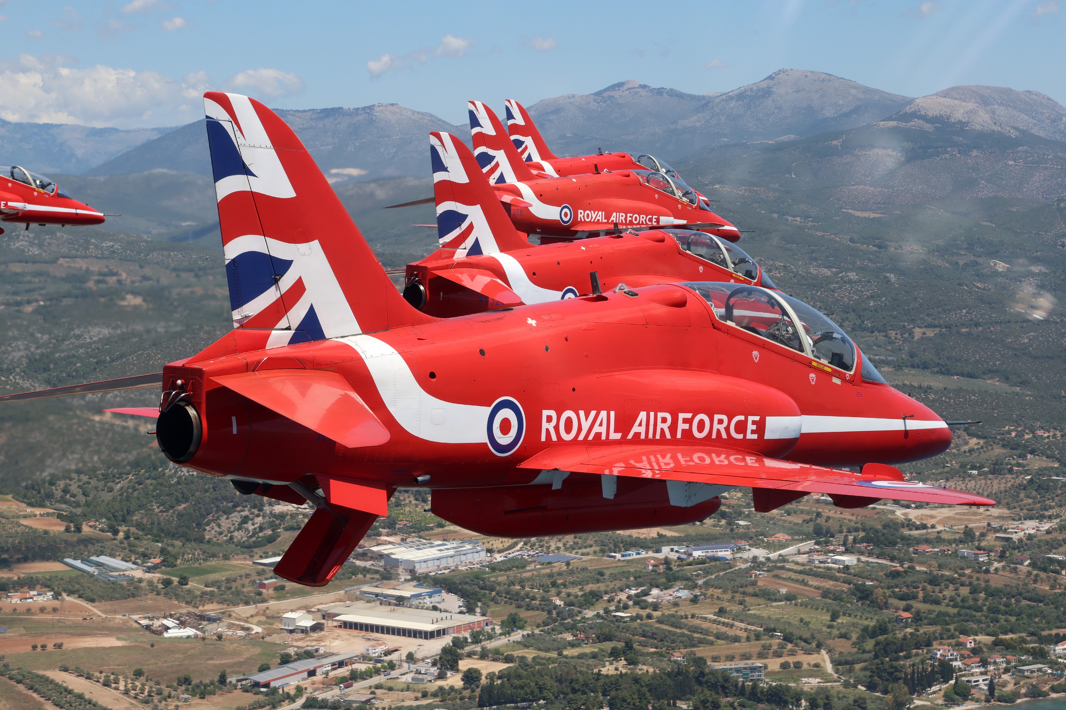 Image shows the Red Arrows in flight over mountains.
